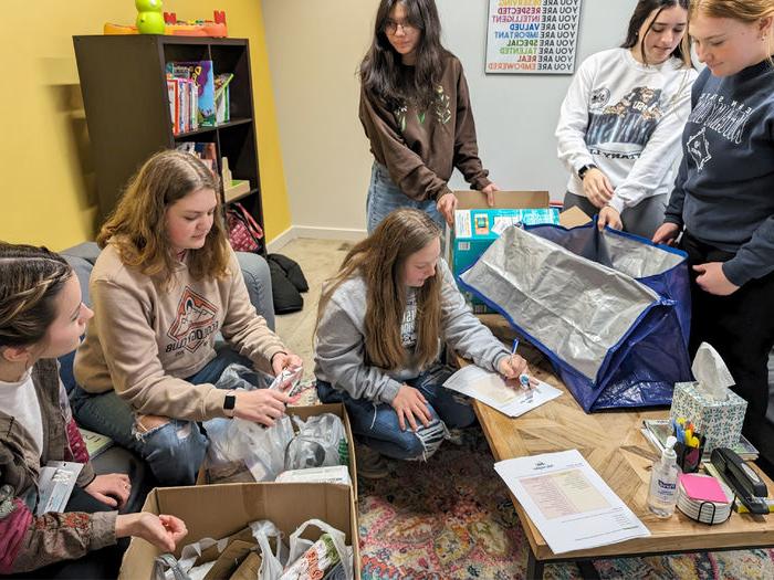 HDFS club members take inventory and organize items at 你好邻居 during the process of making baby bags during their visit.